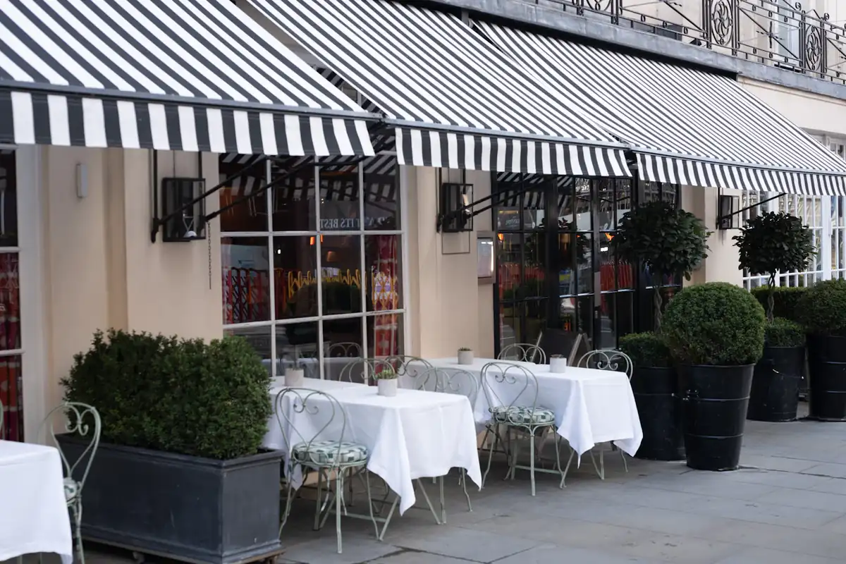 Black and white striped awnings shading tables outside a shop front