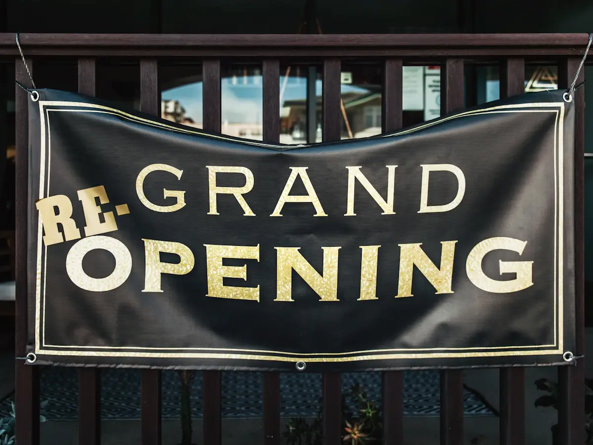 A black PVC banner with gold lettering, eyeleted and tied to railings