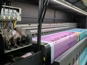 A wide-format printer printing a pink and blue banner
